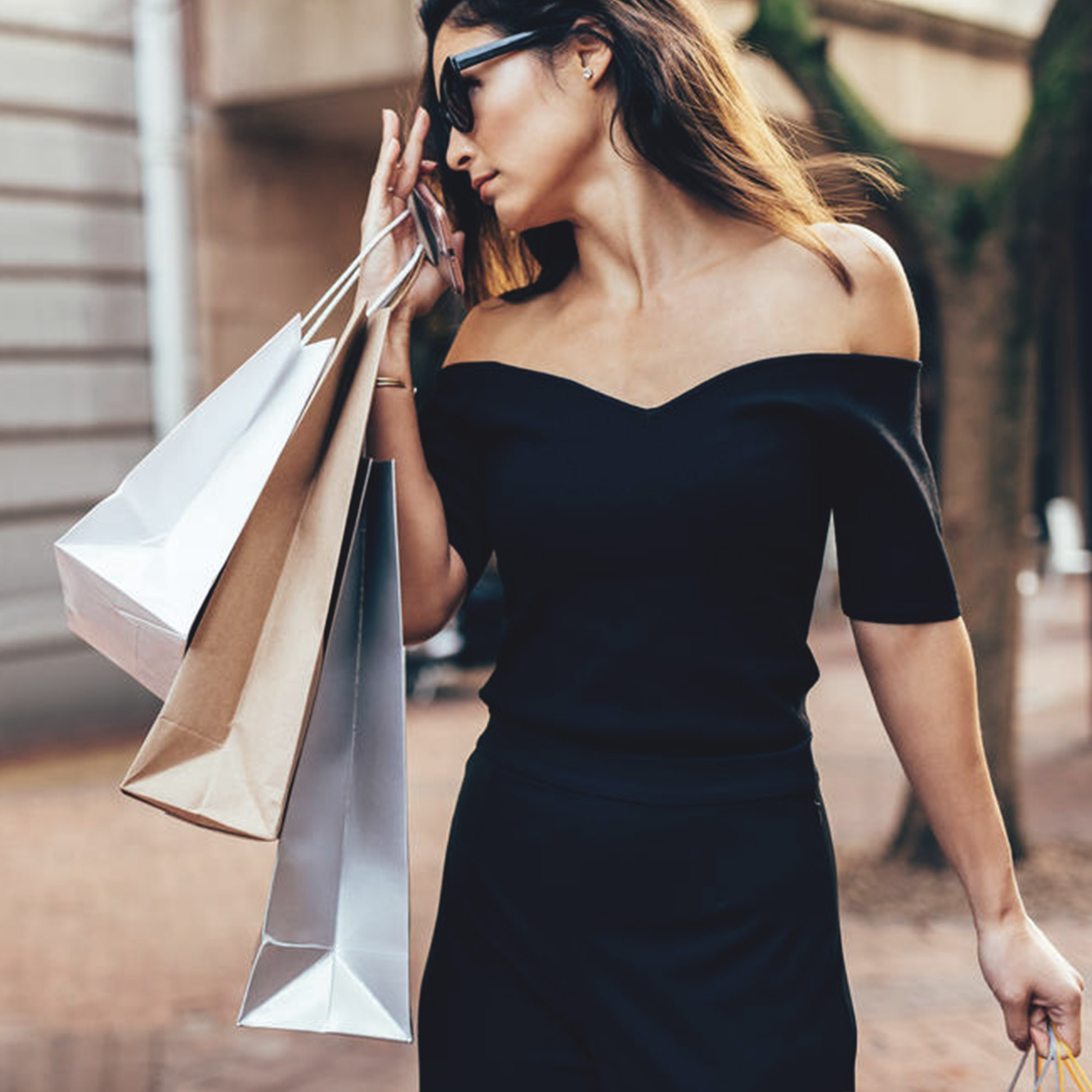 donna con vestito nero e buste shopping